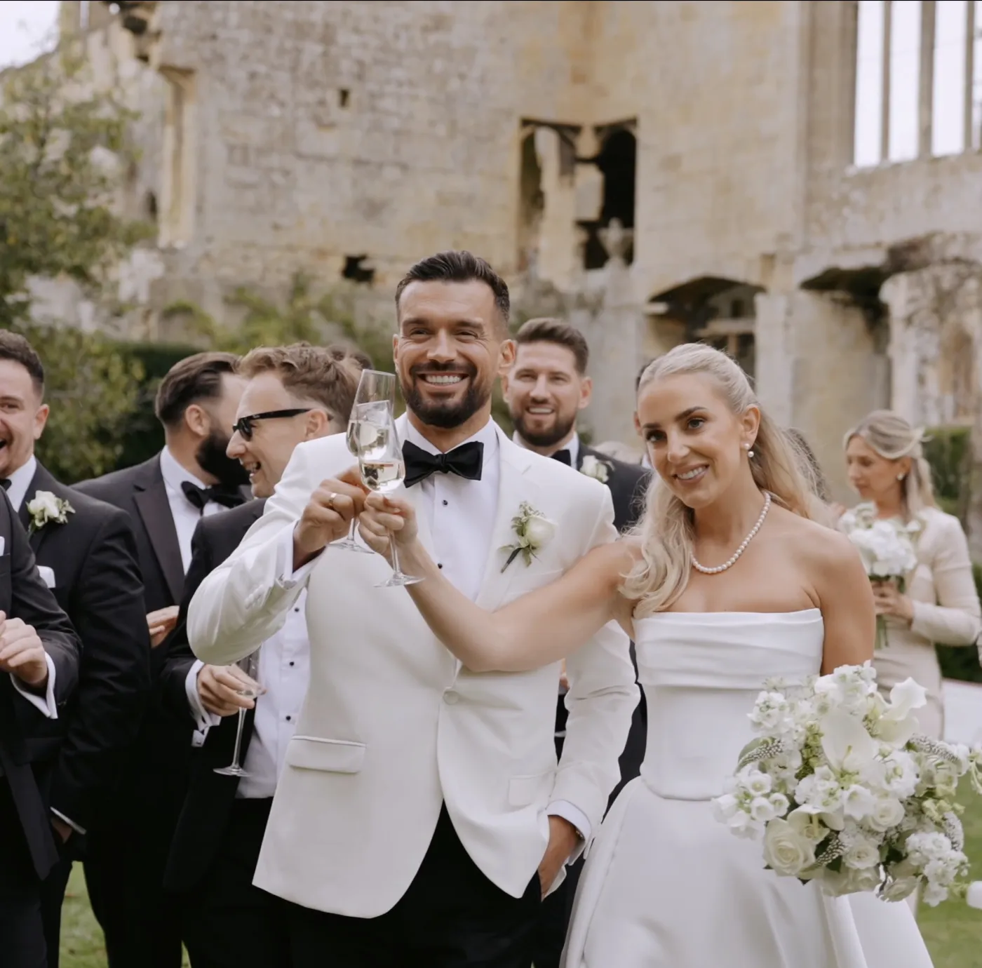 A bride and groom raising a toast with their wedding party, from a PS Visuals film